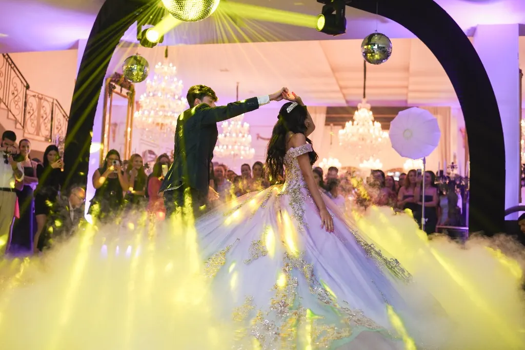 Valsa dos 15 anos: a debutante rodopia com o par sob fumaça baixa e globos de espelho — festa de 15 anos em Brasília
