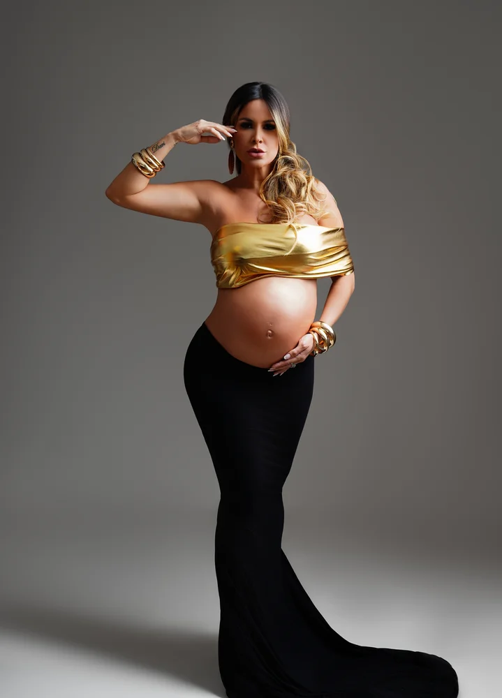 Gestante em vestido dourado, close com a barriga em destaque — ensaio gestante em estúdio