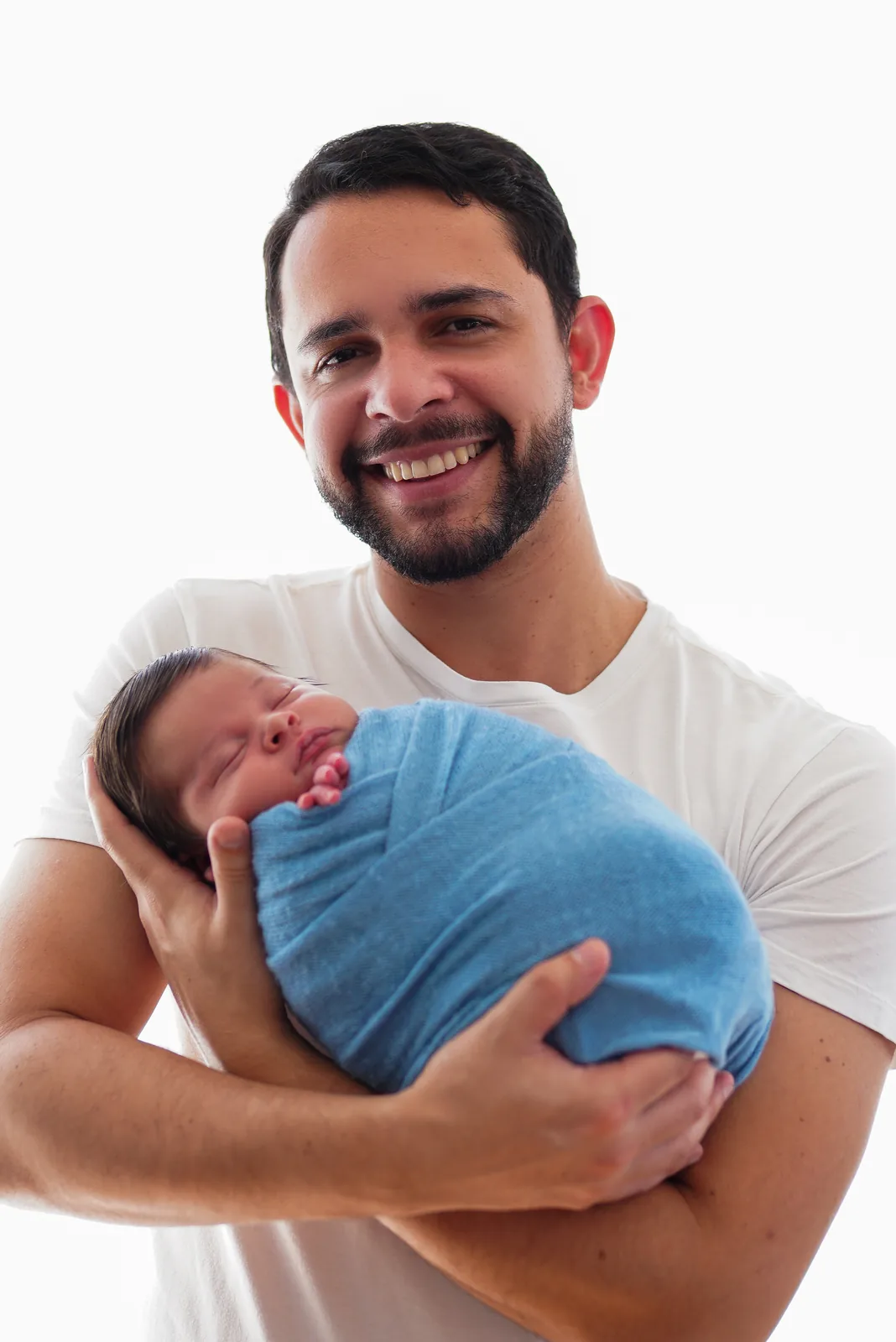 Pais sorridentes segurando juntos o recém-nascido enrolado em manta azul