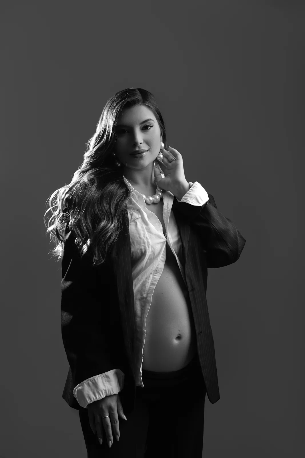 Gestante em blazer e colar de pérolas, mesma cena em preto e branco