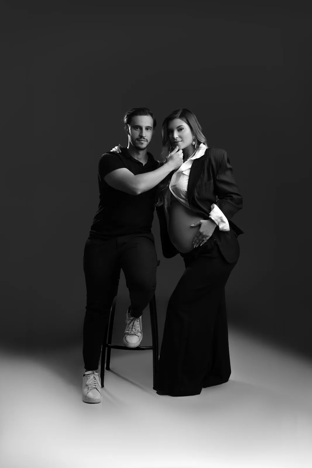 Casal grávido, blazer e calça pantalona, mesma cena em preto e branco