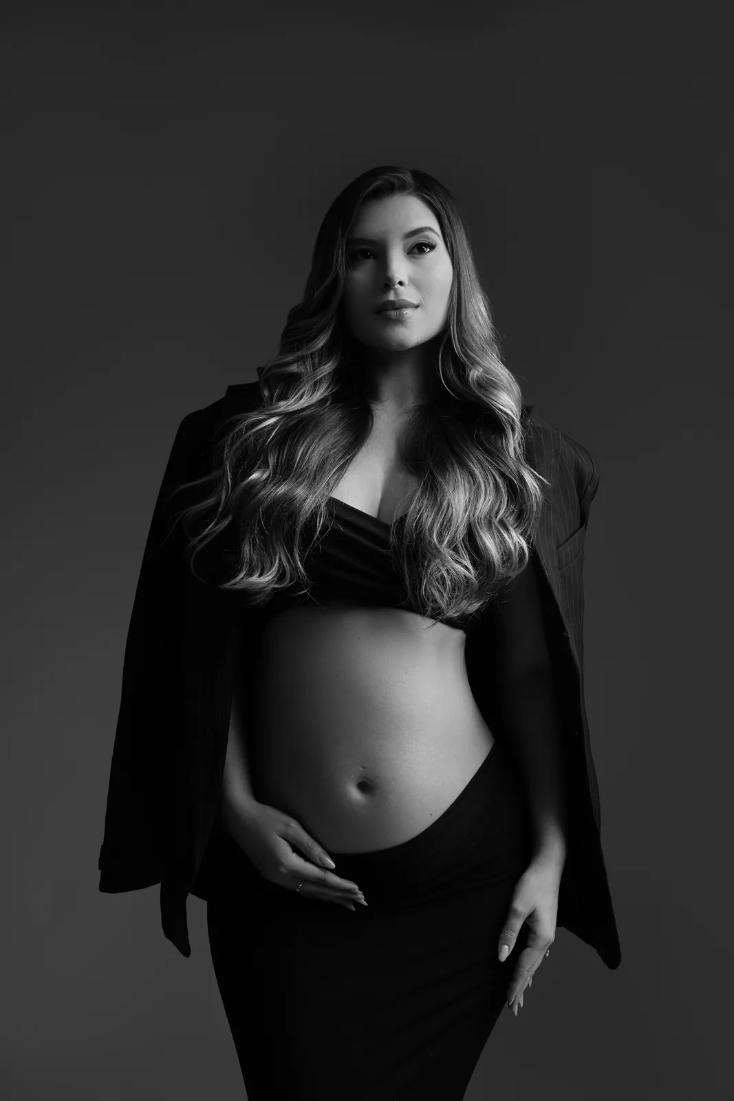 Gestante em top preto e blazer, mesma cena em preto e branco