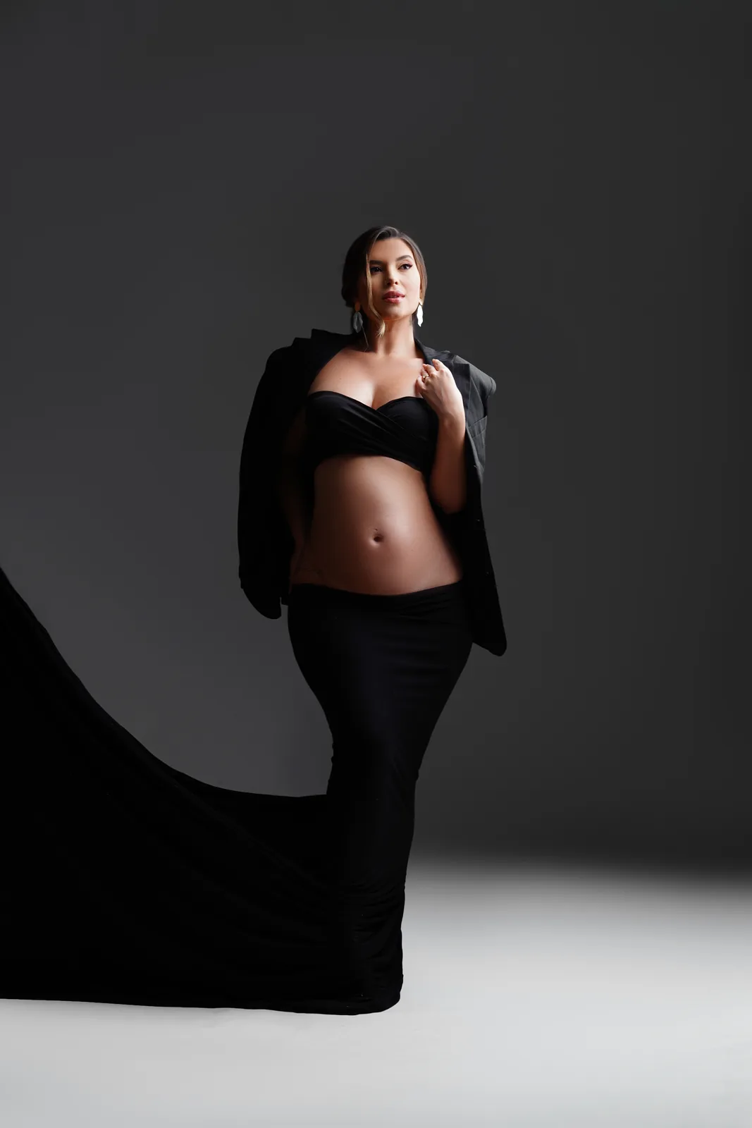 Gestante em vestido preto sereia com blazer, outro ângulo, corpo inteiro