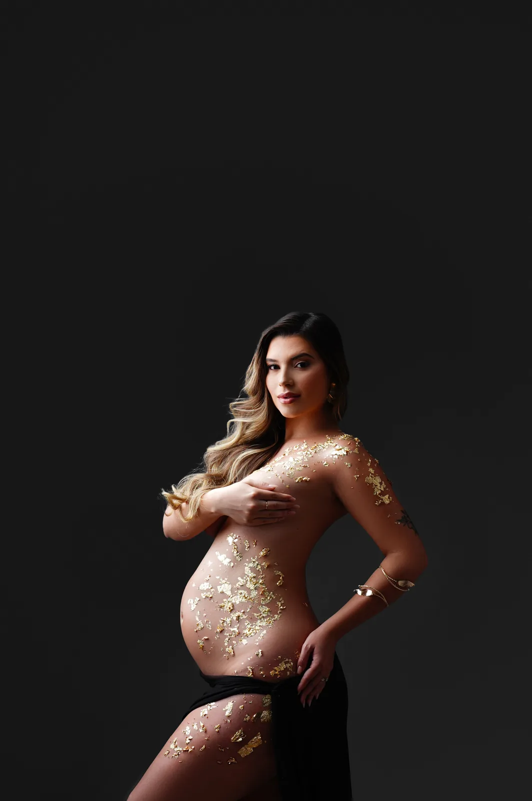Gestante com folhas de ouro na pele, mesma cena em preto e branco