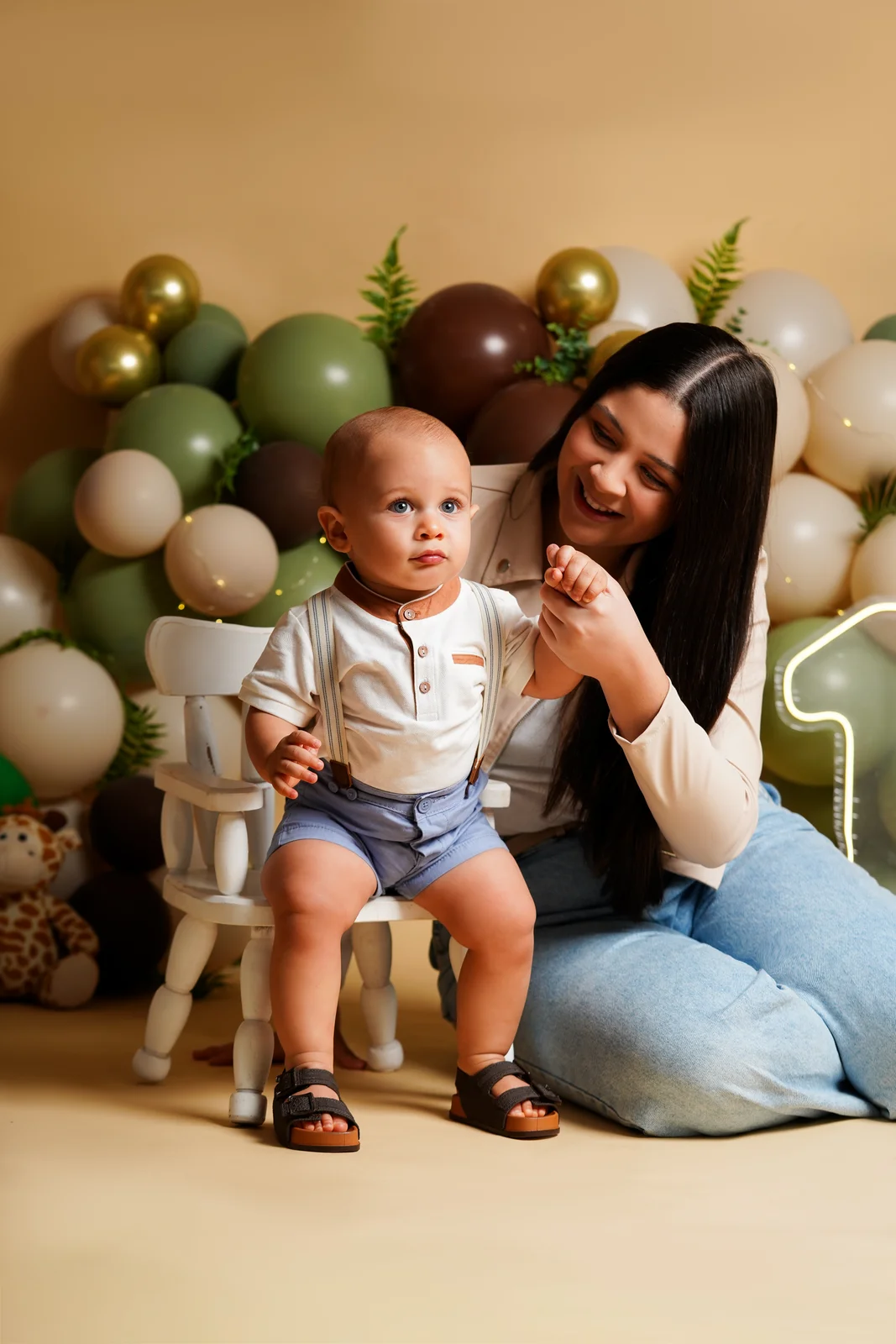 Bebê sentado na cadeirinha com a mãe ao lado, sorrindo — ensaio smash the cake