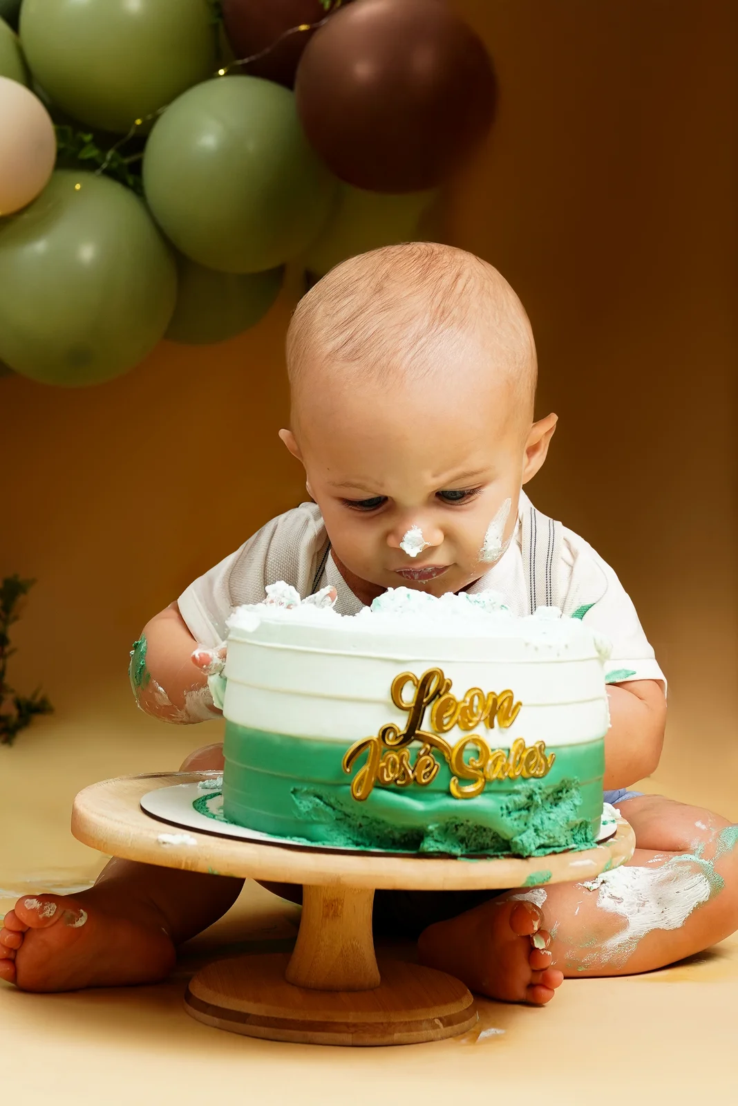 Bebê sentado com as mãos no bolo, todo sujo de glacê — ensaio smash the cake