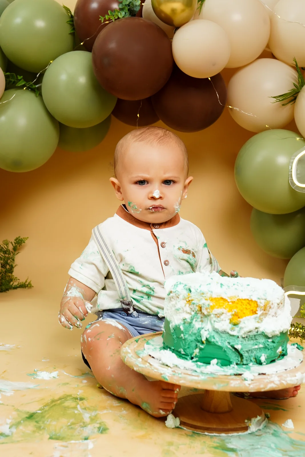 Bebê brincando com o bolo, mãos sujas de glacê verde — ensaio smash the cake