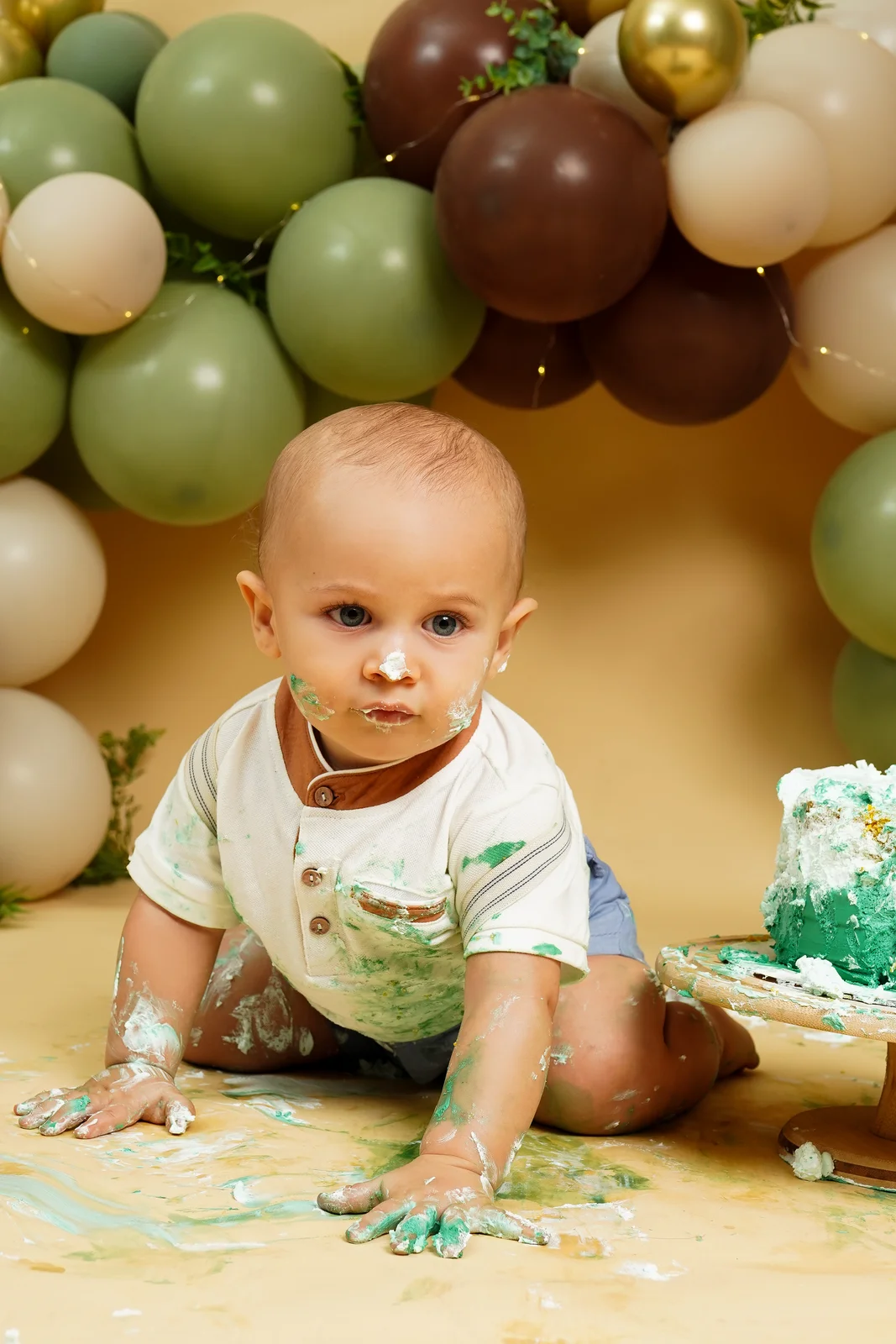Bebê sorrindo pra câmera, sentado no chão — ensaio smash the cake
