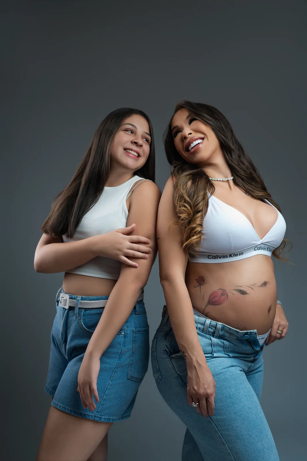 Gestante em família — marido, ela e a filha em abraço em grupo, todos sorrindo