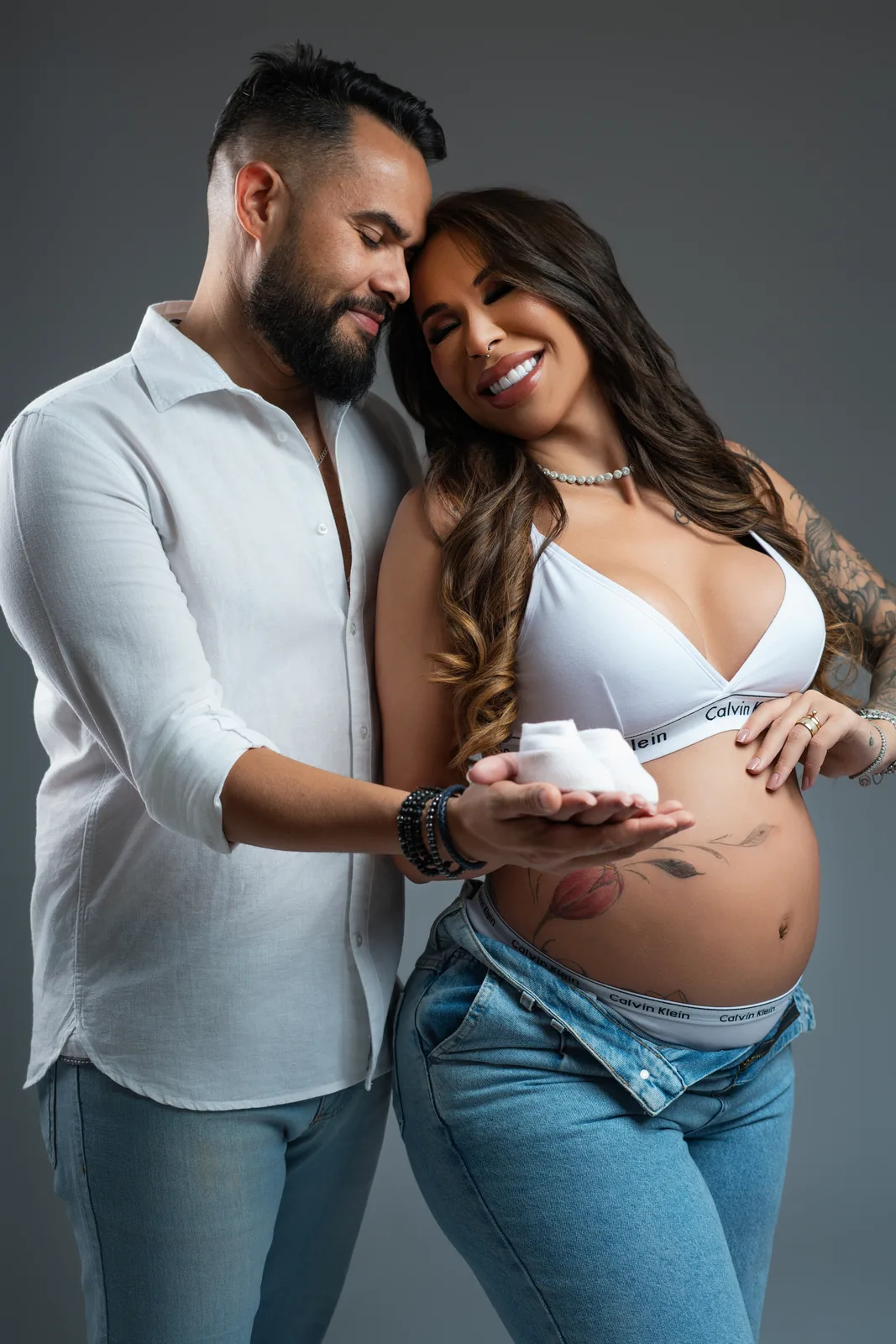 Gestante em top branco Calvin Klein, cabelo ao vento, retrato de perto sorrindo