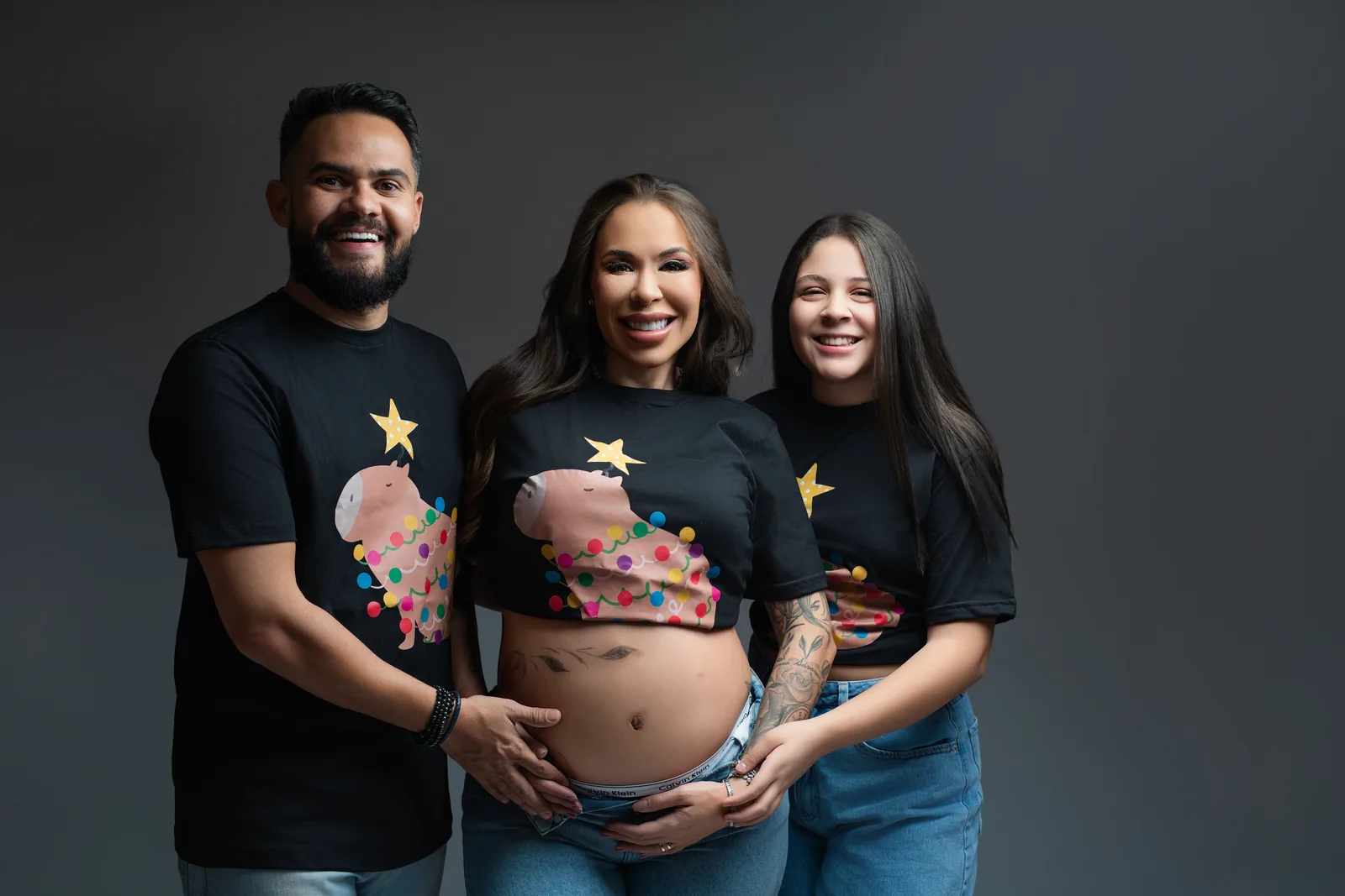 Gestante em conjunto de lingerie preta Calvin Klein, corpo inteiro de perfil, tatuagens na perna