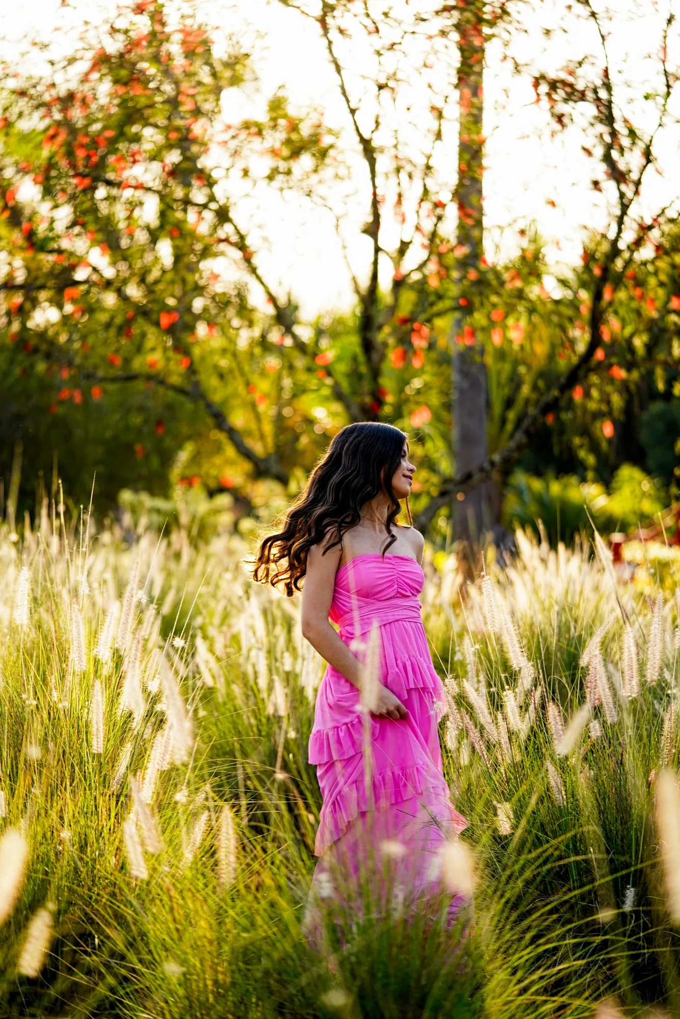 Debutante de vestido rosa caminhando entre capim dourado ao entardecer na Casa da Ana