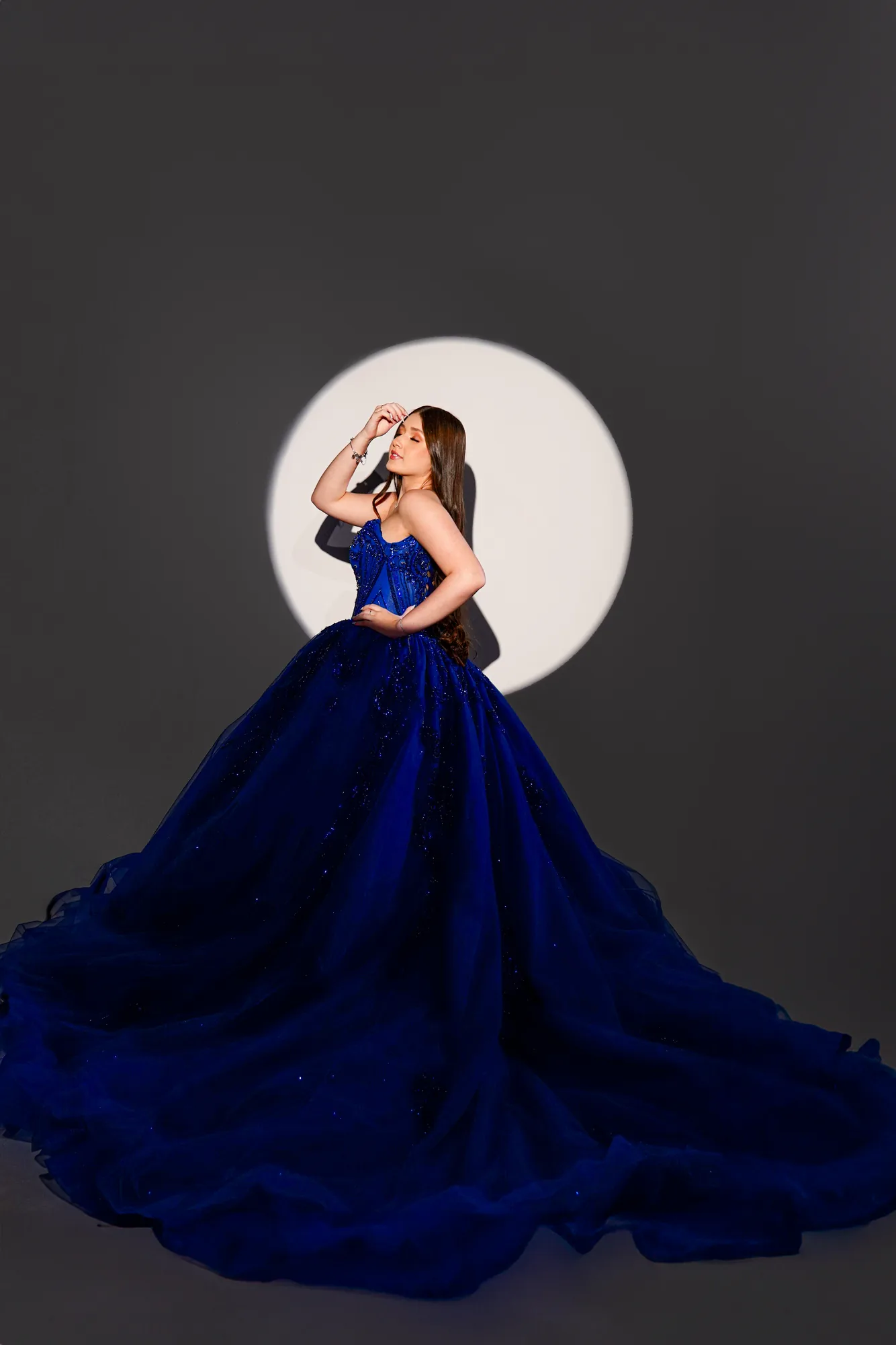 Debutante de vestido azul-marinho volumoso segurando buquê de rosas azuis, ensaio em estúdio
