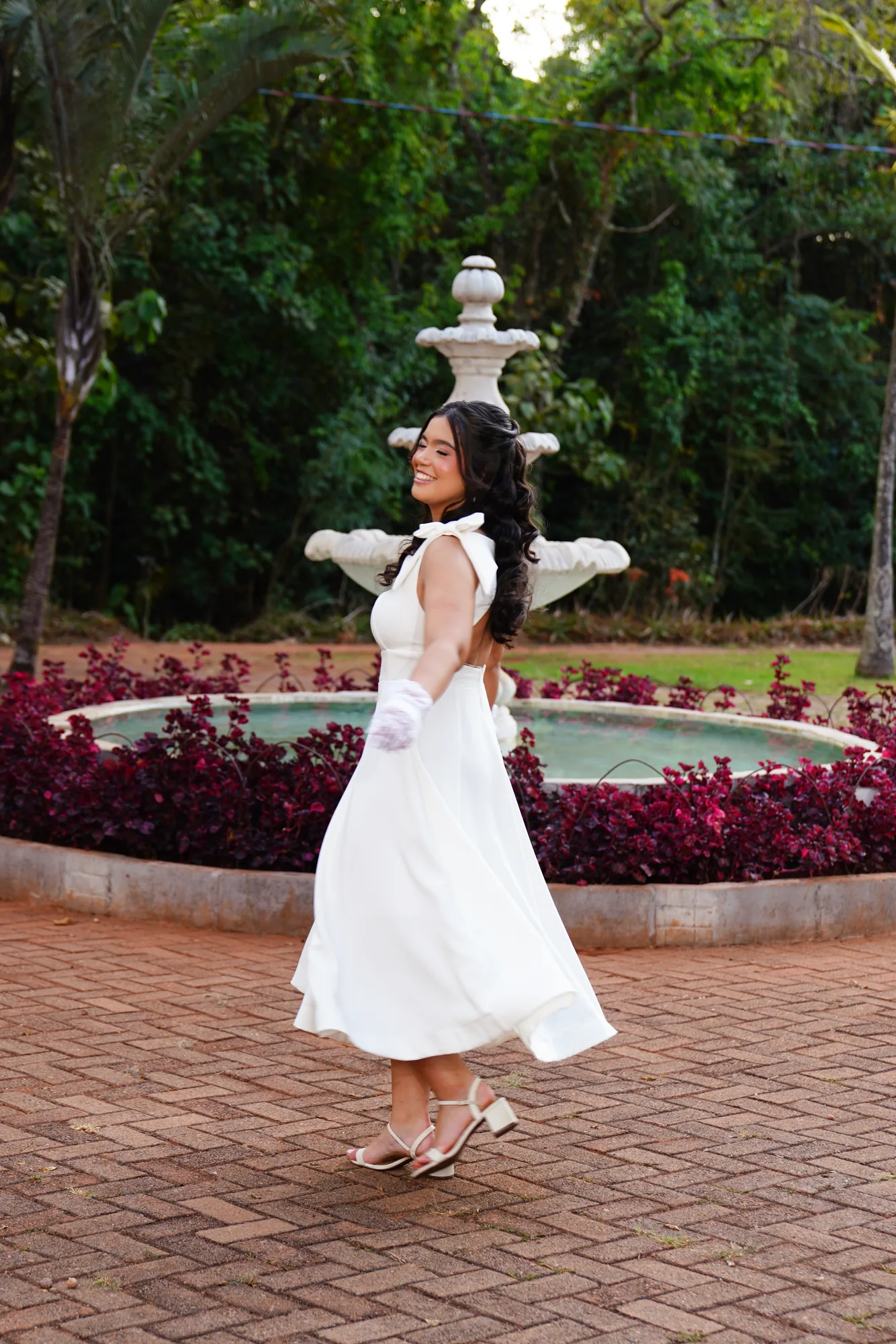 Debutante de vestido branco rodopiando perto da fonte do Jardim Botânico de Brasília