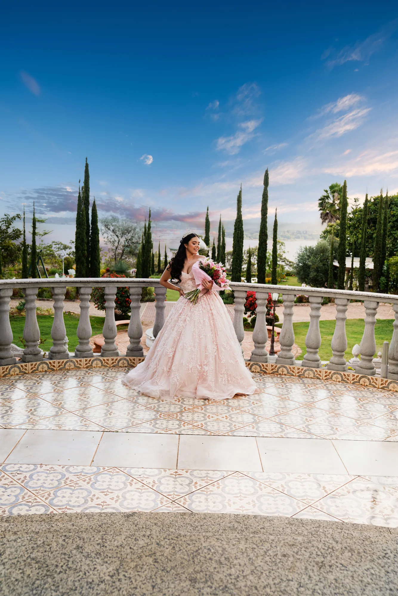 Debutante descendo a escadaria dourada da Villa Giardini, vestido rosé volumoso — prévia de 15 anos em Brasília