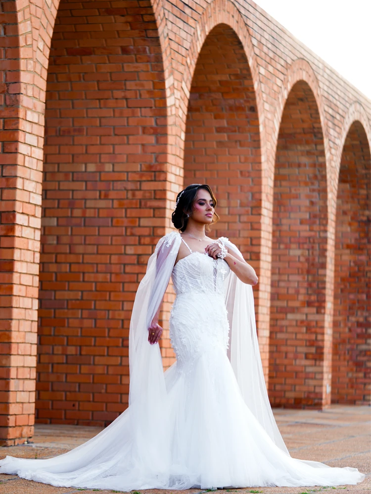 Noiva em vestido de sereia e capa de tule, entre arcos de tijolo — retrato de casamento em Brasília