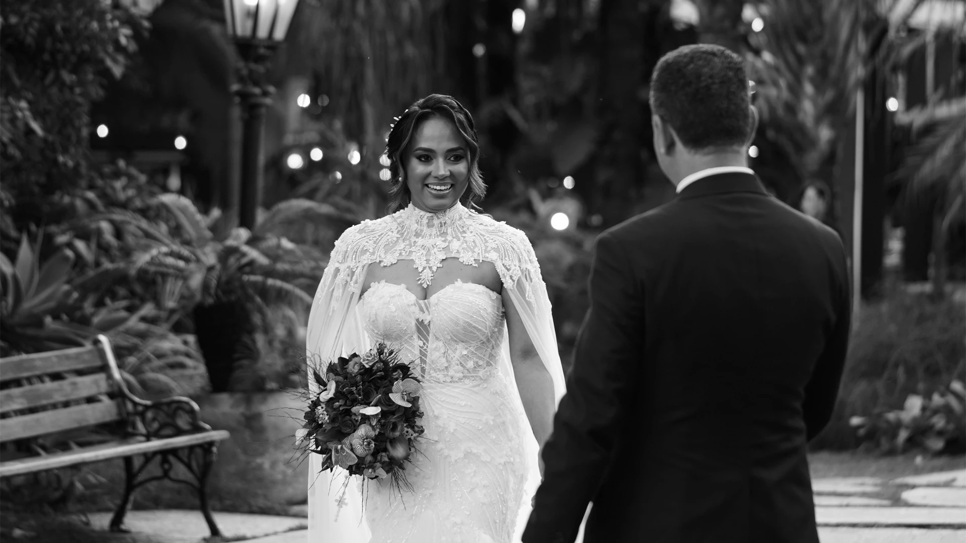 Noiva sorrindo ao ver o noivo pela primeira vez, em jardim à noite, em preto e branco — first look de casamento em Brasília
