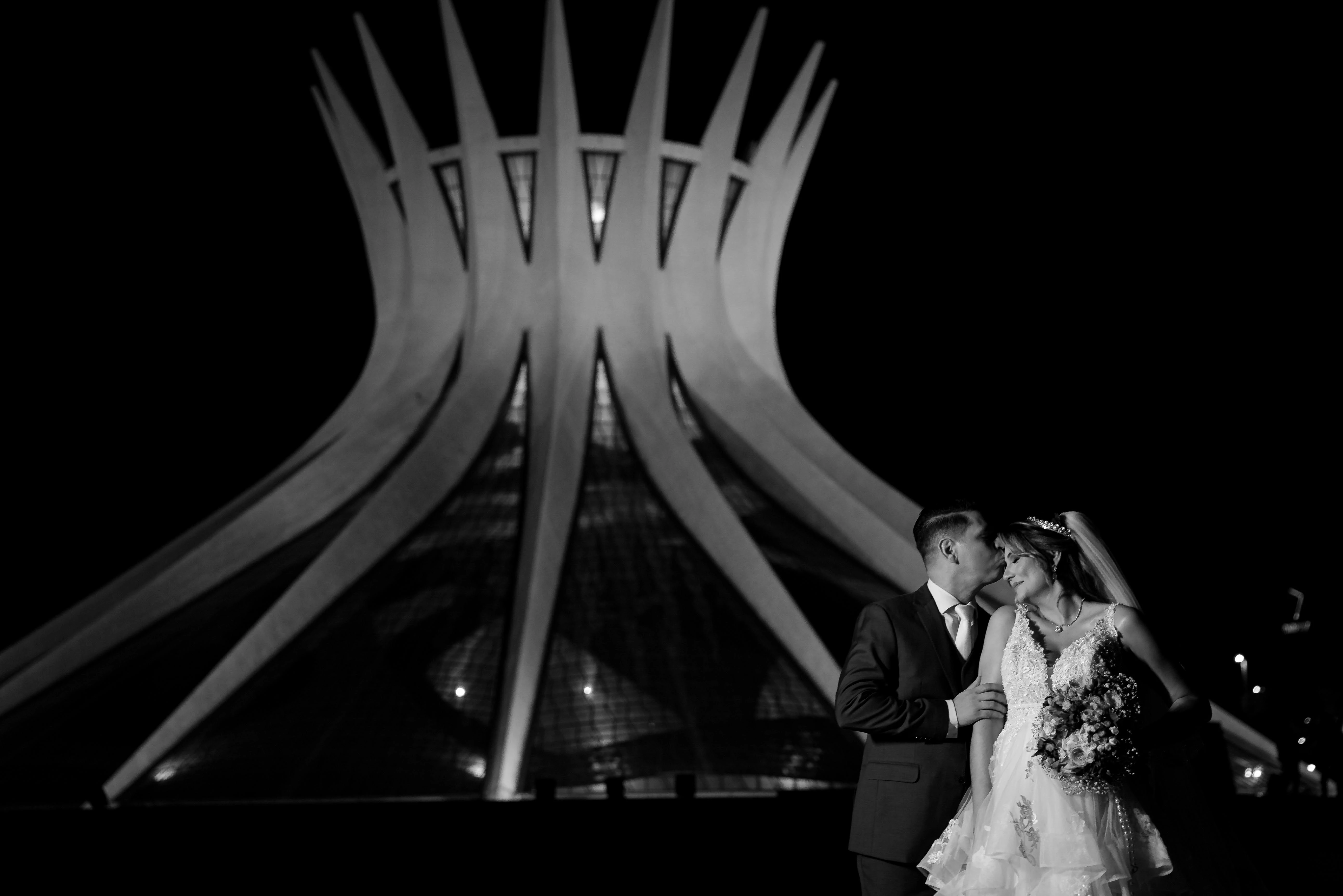 Silhueta dos noivos em frente à Catedral de Brasília iluminada à noite, em preto e branco — retrato icônico de casamento em Brasília