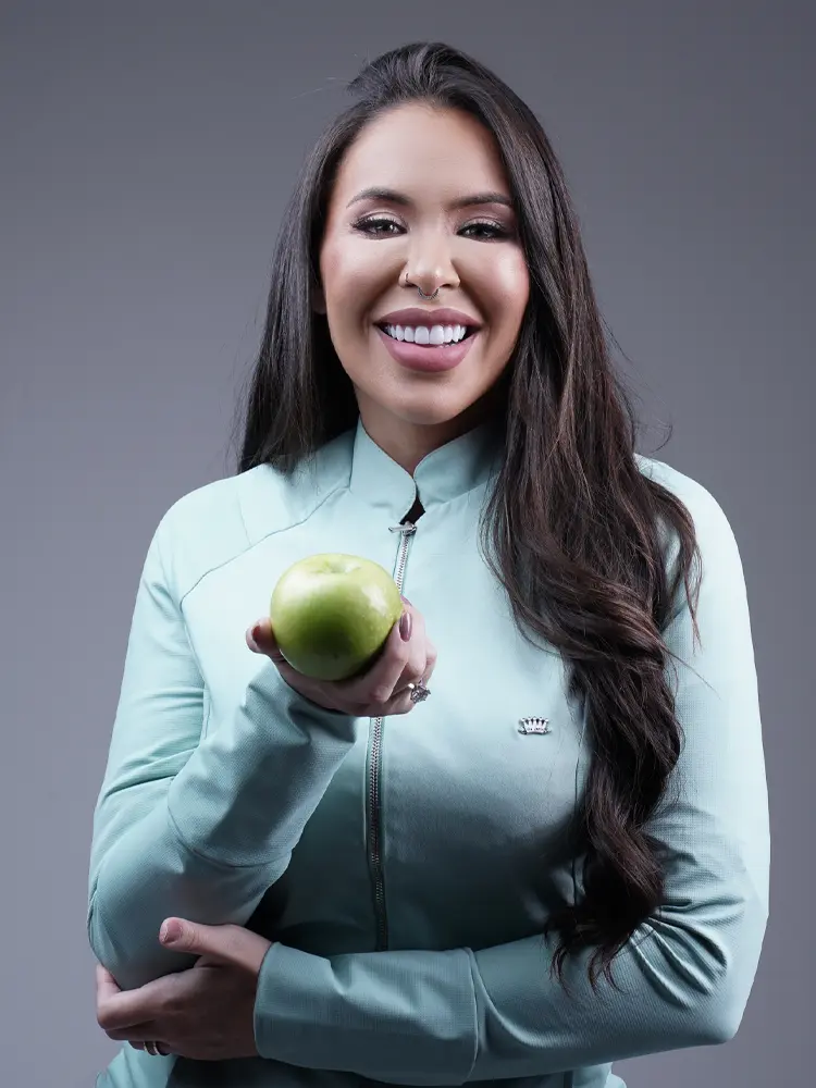 Retrato feminino sorridente em jaqueta verde-água segurando uma maçã — ensaio feminino em estúdio, Brasília